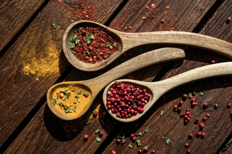 three wooden spoons filled with different types of spices